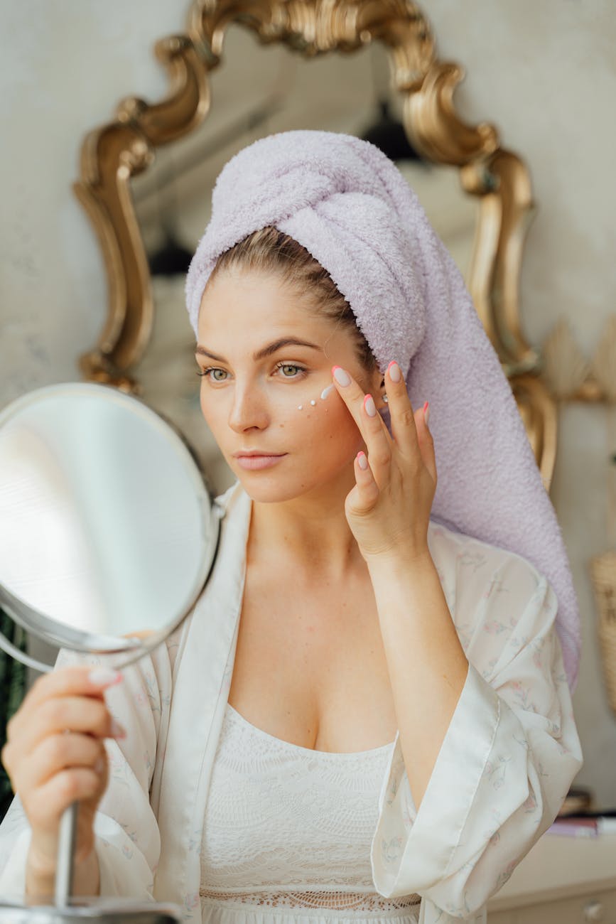 woman looking in the mirror and applying a face cream
