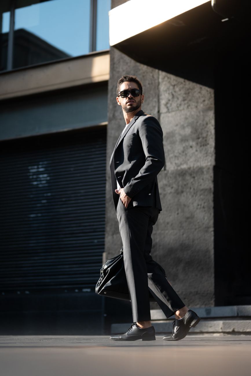 man in a suit and sunglasses walking through a street
